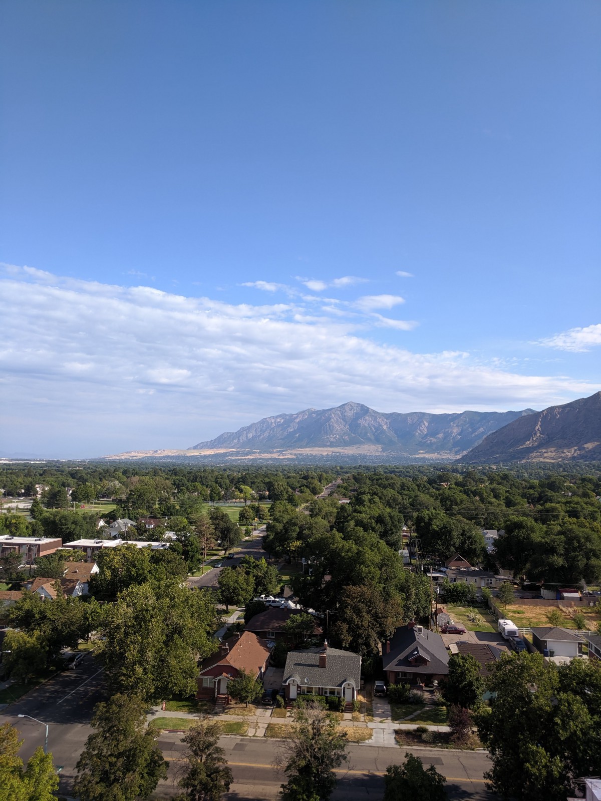 A scenic view of a lush green landscape with mountains in the background and a clear blue sky overhead.