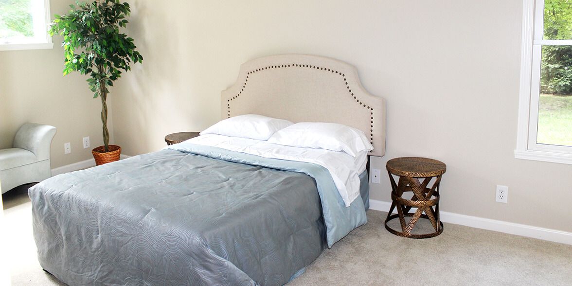 A tidy bedroom featuring a neatly made bed with a stylish headboard and an adjacent nightstand.