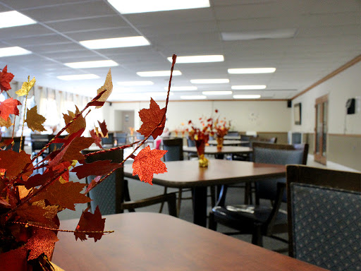 A cozy dining area decorated with autumn-themed accents, featuring tables and chairs arranged for gathering.