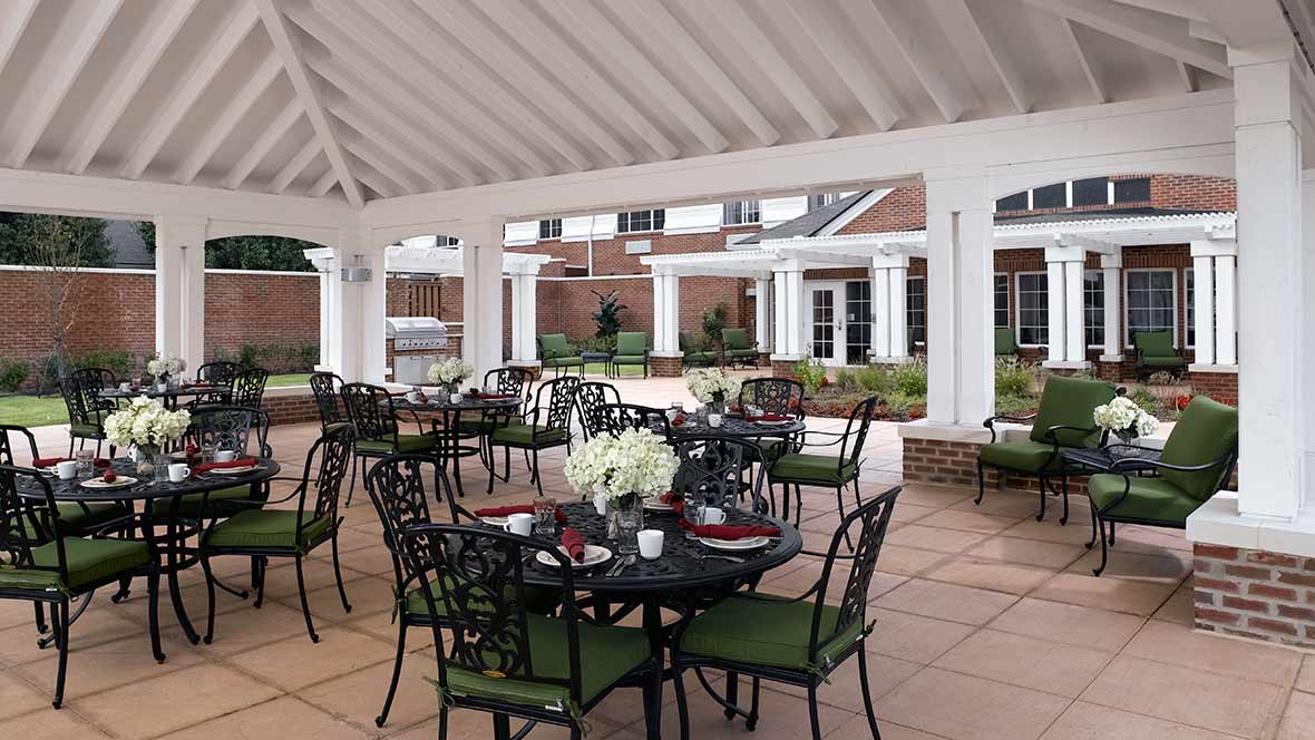 An inviting outdoor patio dining area under a gazebo with elegant tables and chairs.