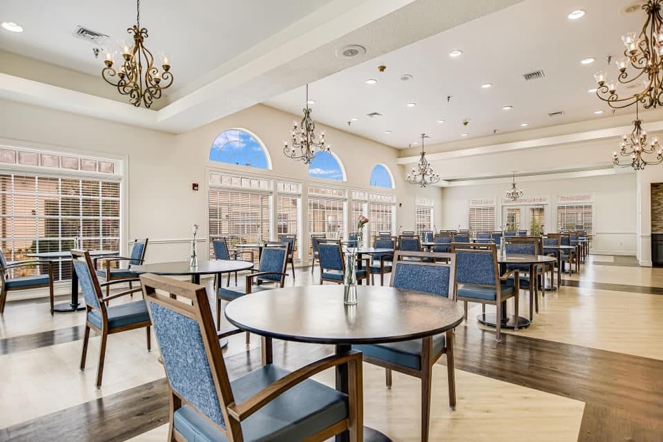 Elegant dining room interior with chandeliers and large windows.