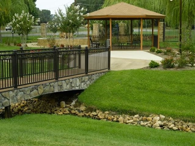 A scenic view of a park featuring a gazebo, bridge, and lush green grass.