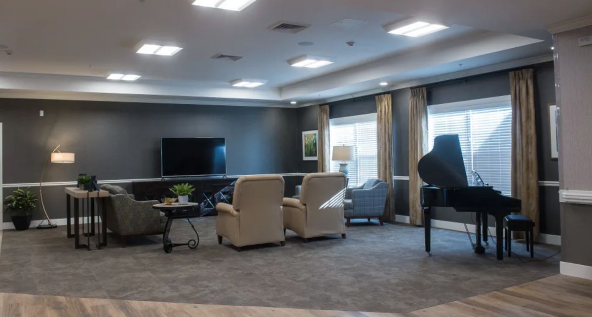 A spacious living room with comfortable seating, a television, and a grand piano.