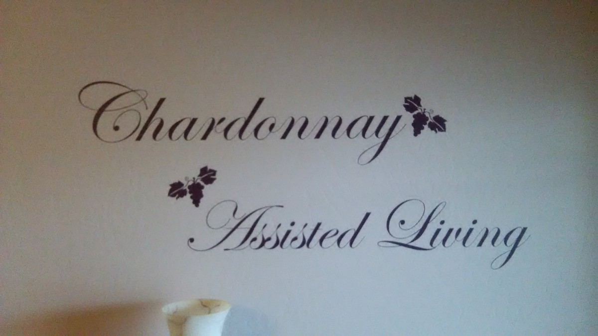 Wall decoration featuring the words 'Chardonnay Assisted Living' with grape illustrations.