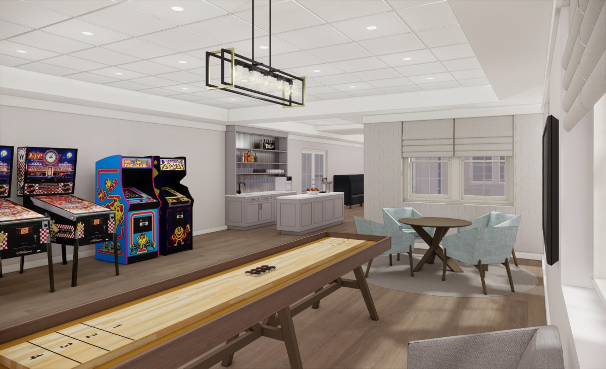 A modern game room featuring an arcade machine, shuffleboard table, and a kitchen area with seating.