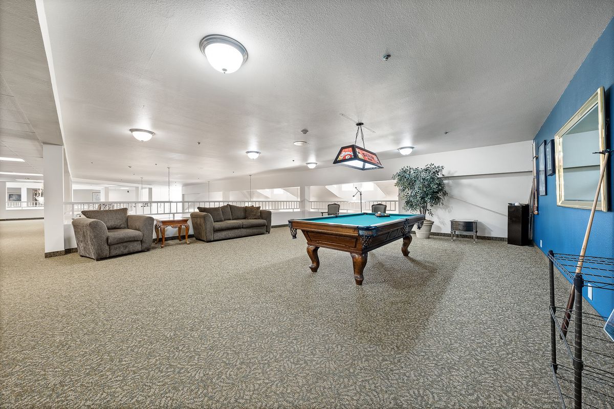 A spacious recreation room featuring a pool table and comfortable seating.