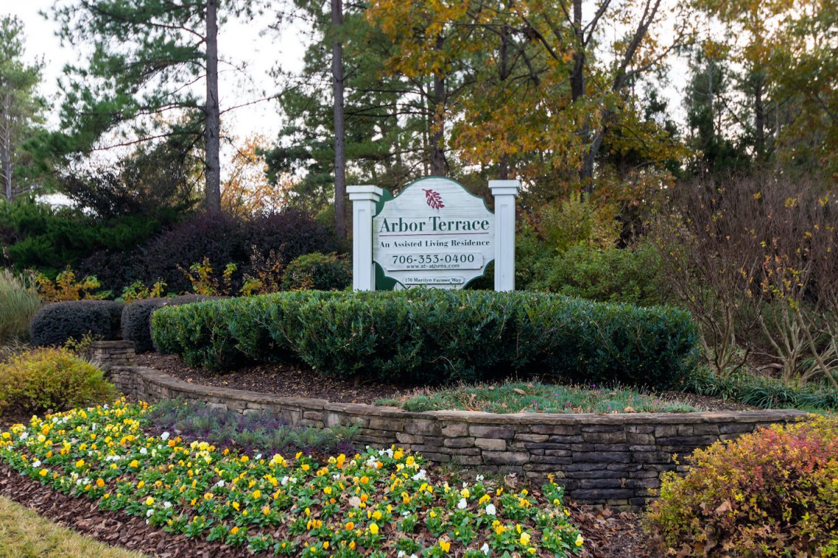 A landscaped entrance sign surrounded by greenery and flowers.
