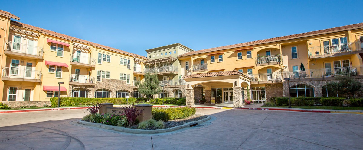 A modern residential building with landscaped surroundings on a sunny day.