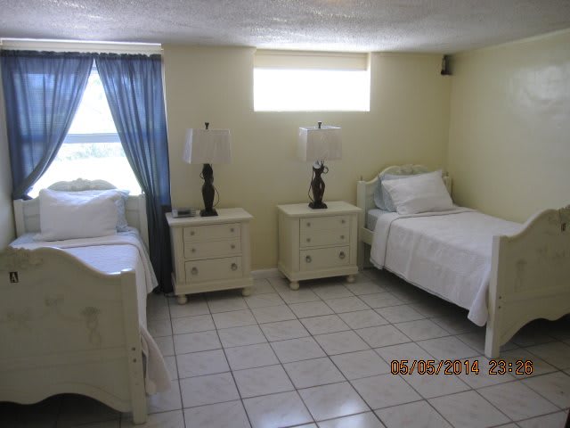 A simple bedroom with twin beds, white furniture, and tiled floor.