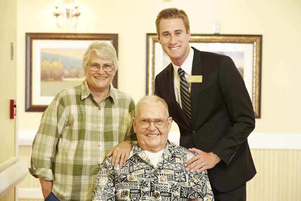 A group of three people smiling together indoors.