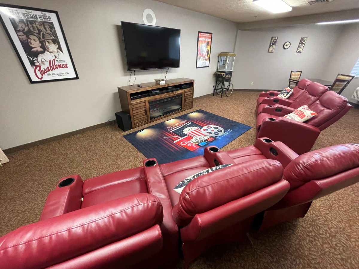 A cozy home theater featuring red recliners, a large TV, and movie-themed decor.