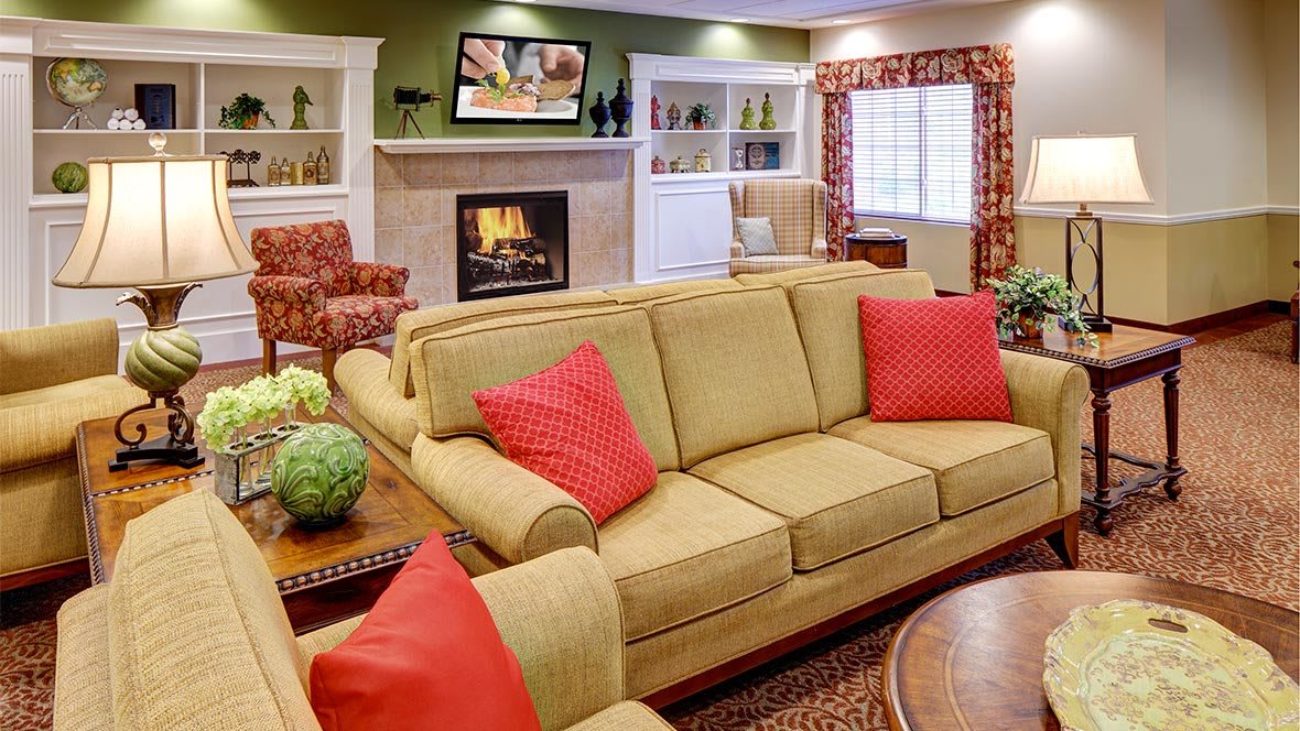 A cozy living room with a beige sofa, red cushions, and a fireplace.
