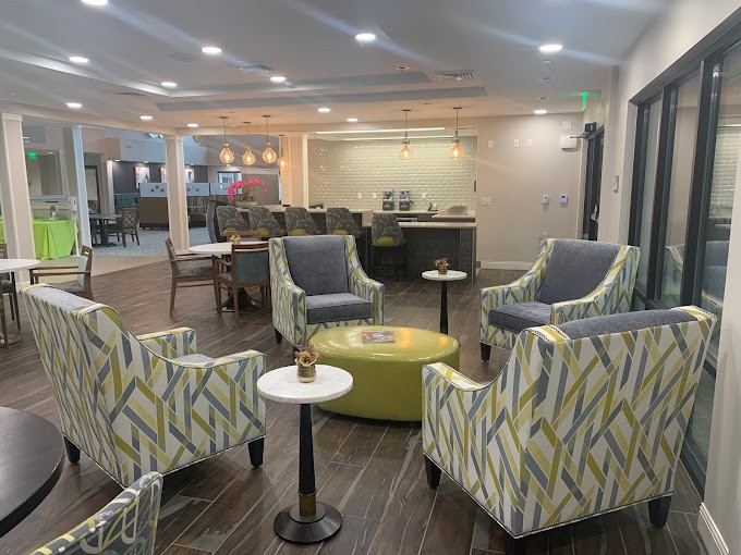 A modern lobby area featuring comfortable armchairs and small tables, with soft lighting creating an inviting atmosphere.