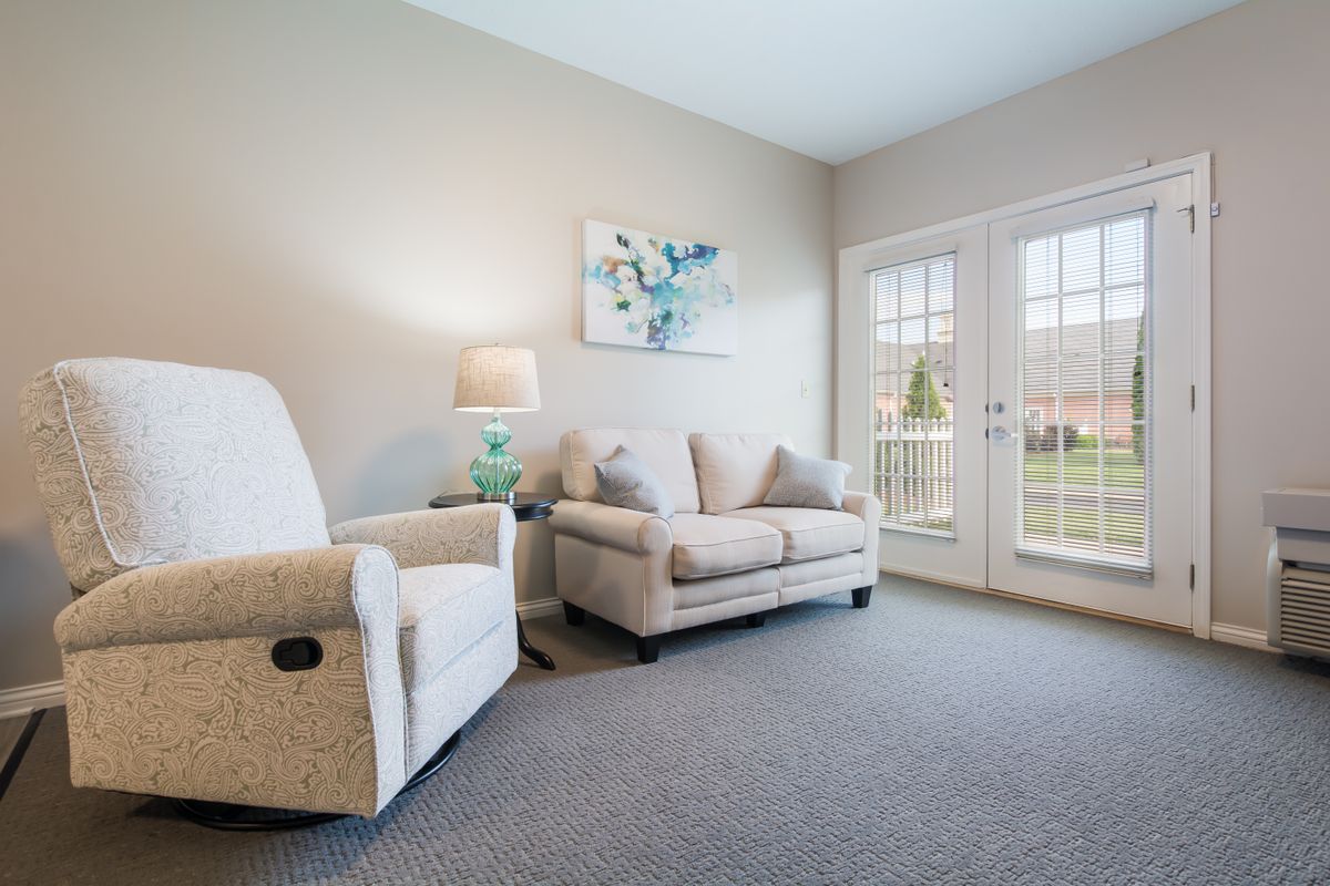 A cozy living room featuring a comfortable sofa and armchair, complemented by a side lamp and artwork on the wall.