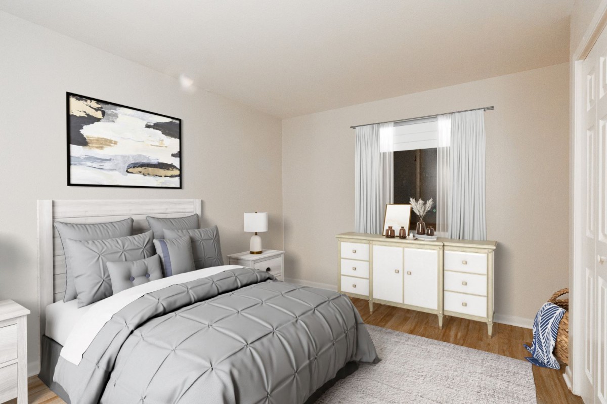 A modern bedroom with gray bedding, a bedside lamp, and a white dresser under a window.