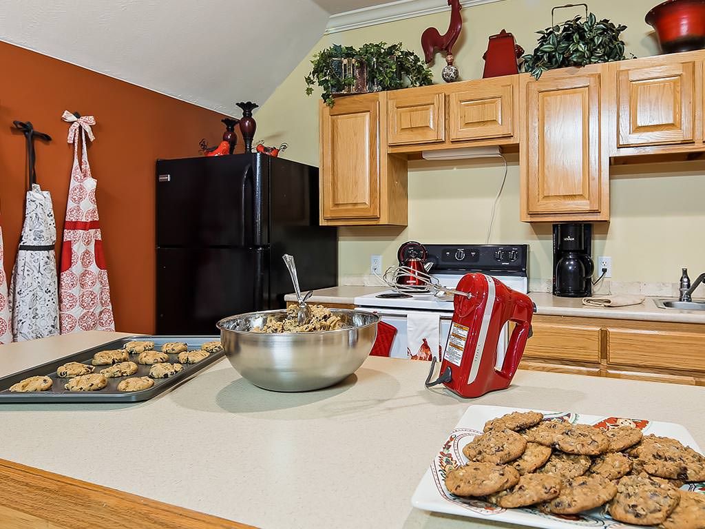 A cozy kitchen setting with freshly baked cookies on the countertop, accompanied by a mixer and baking supplies.