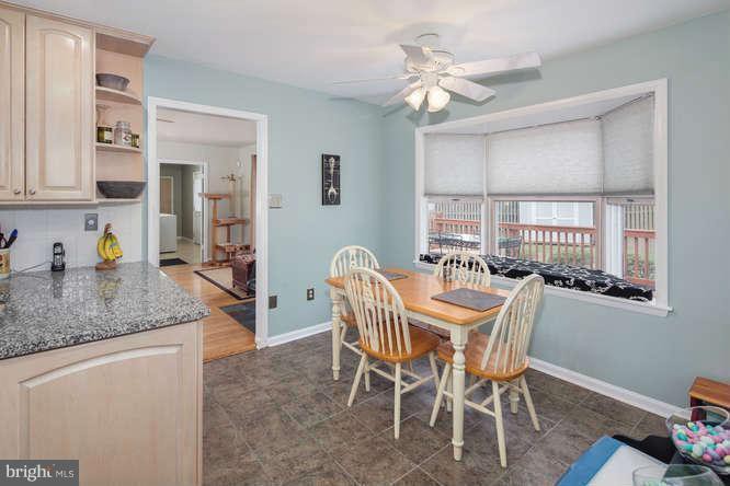 A cozy kitchen dining area with a wooden table and chairs, ceiling fan, and window blinds.