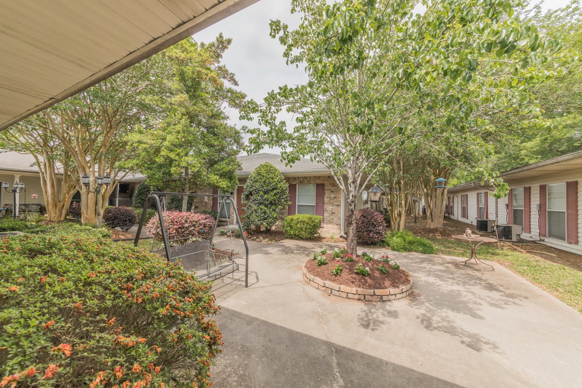 A peaceful courtyard with a garden swing and lush greenery.