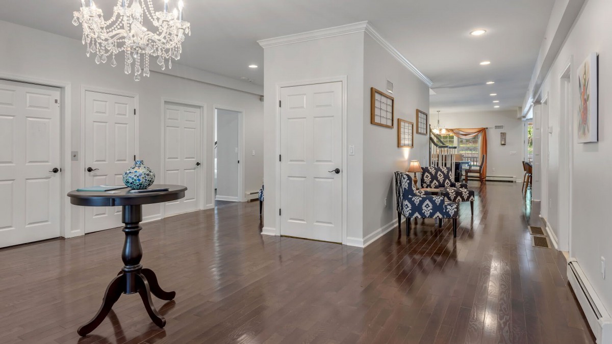 A modern and elegantly designed hallway with wooden floors and a chandelier.