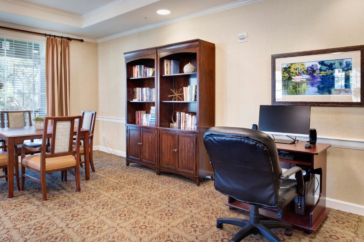 A well-organized office space featuring a desk with a computer, a comfortable chair, and a bookshelf filled with books.