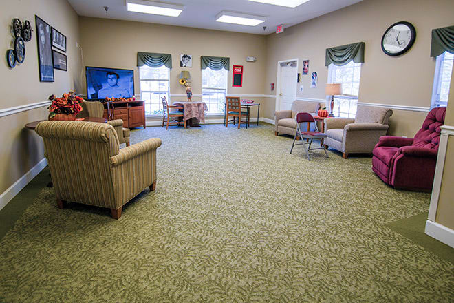 A cozy living room with comfortable seating, a carpeted floor, and a television.