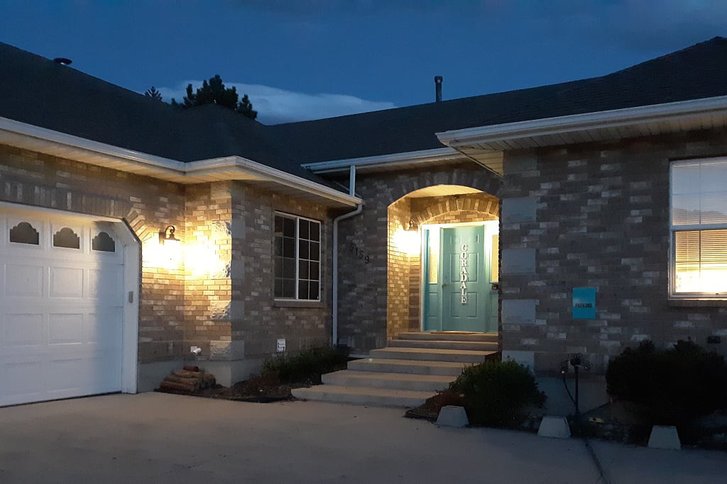 A well-lit house entrance at night with brick exterior and a front porch.
