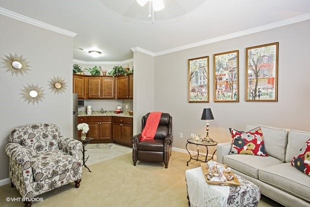 A cozy living room featuring a mix of patterned and solid-colored furniture, accented with colorful wall art.