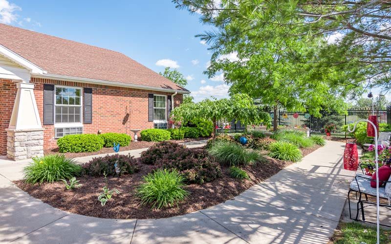 A charming brick house with beautifully landscaped gardens and a winding sidewalk.