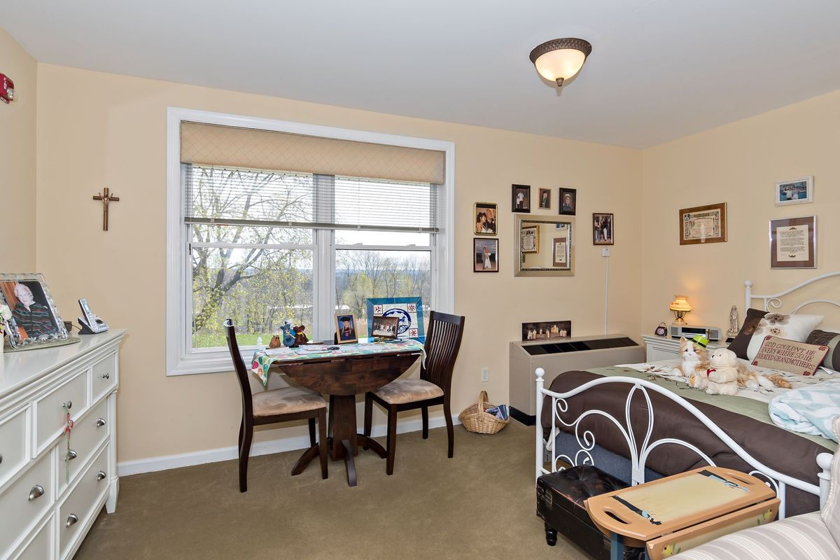 A cozy bedroom with a small dining area by the window and decorative photo frames on the walls.