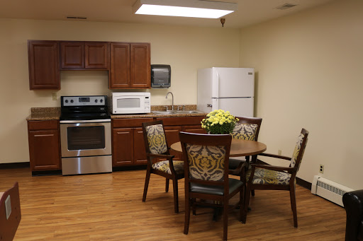 A cozy kitchen and dining area featuring modern appliances and a round table with decorative chairs.