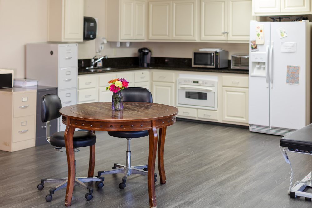 A cozy kitchen with a wooden table and chairs, surrounded by modern appliances and white cabinets.