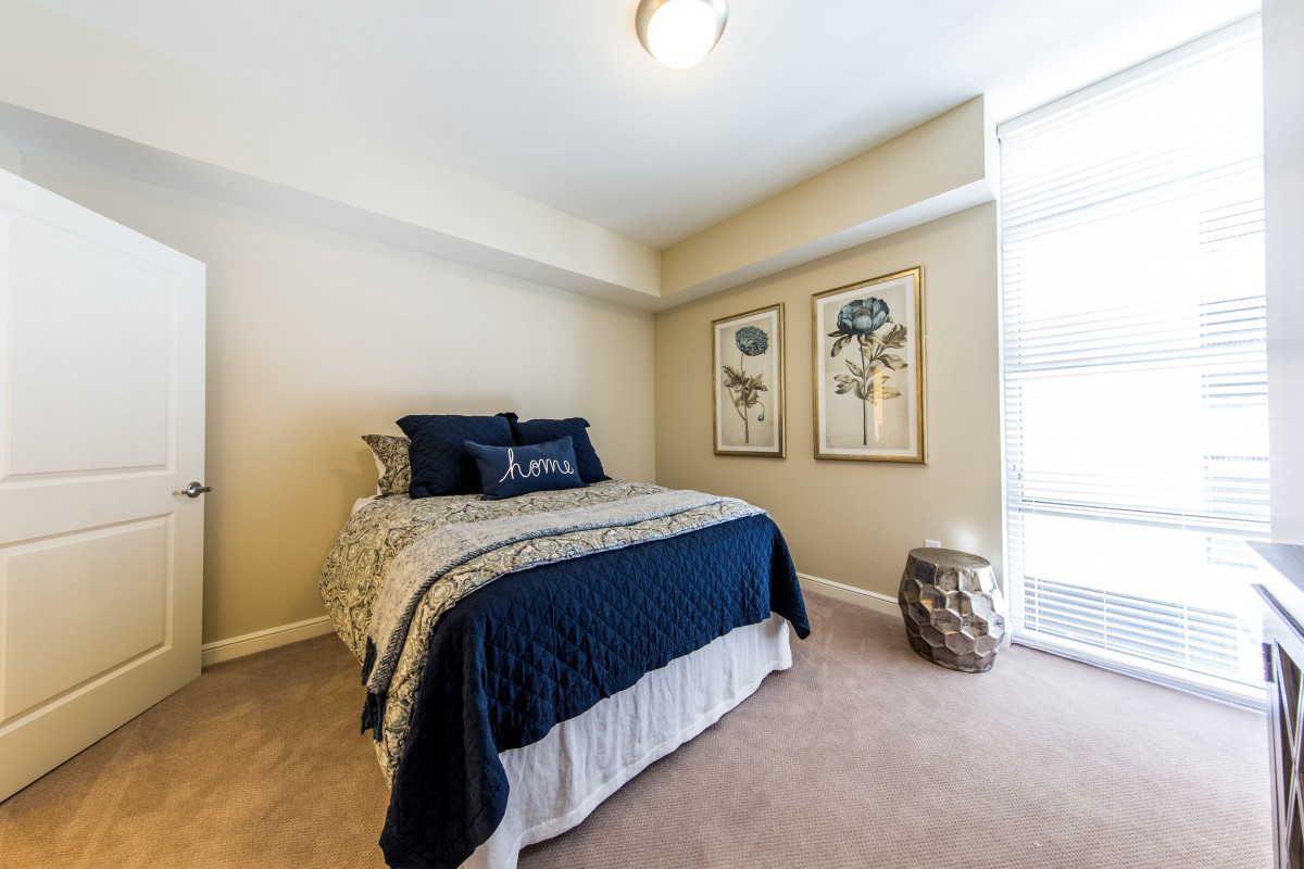 A modern bedroom featuring a neatly made bed with blue and white bedding, complemented by decorative artwork on the walls.