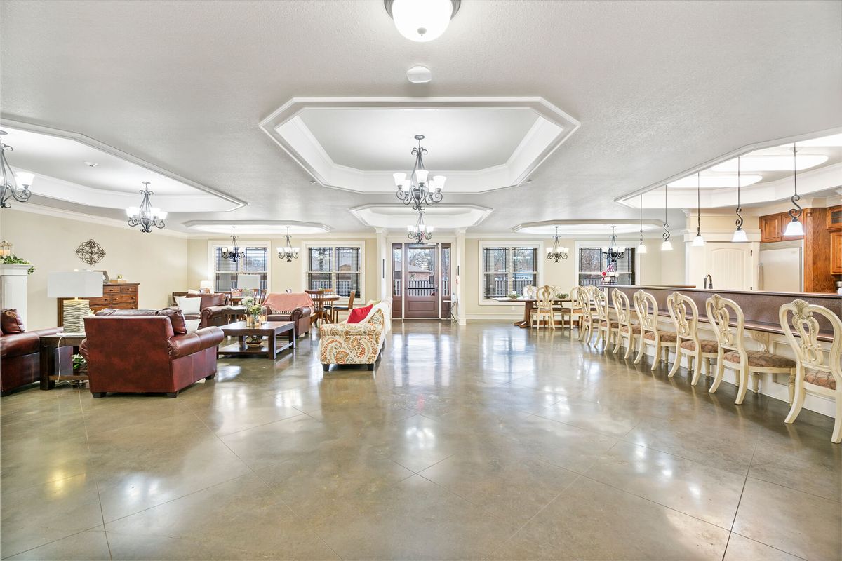 A spacious and well-lit living and dining area featuring elegant furnishings and multiple chandeliers.