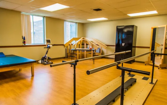 A physical therapy room with exercise equipment and parallel bars.