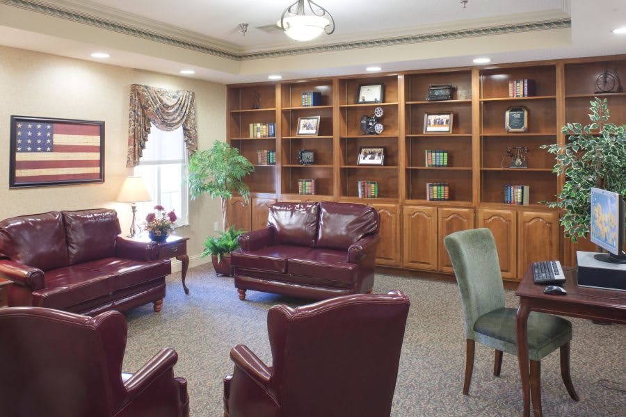 A cozy living room with leather furniture and a wall of bookshelves.