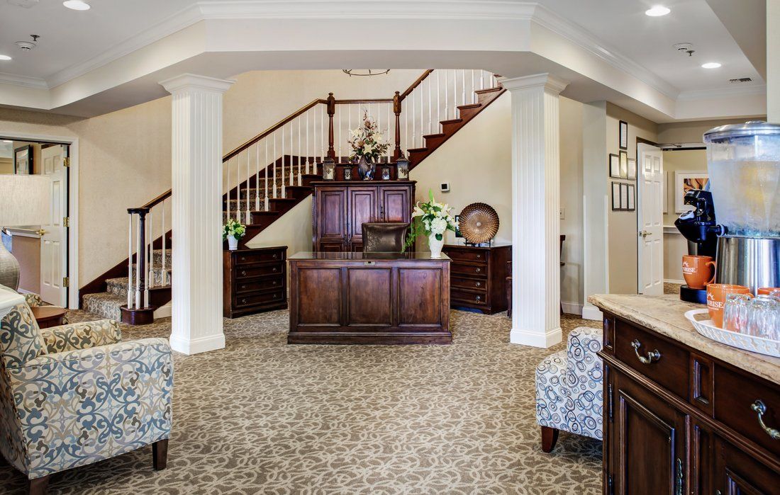 A spacious lobby area featuring a wooden reception desk, decorative elements, and prominent stairs.