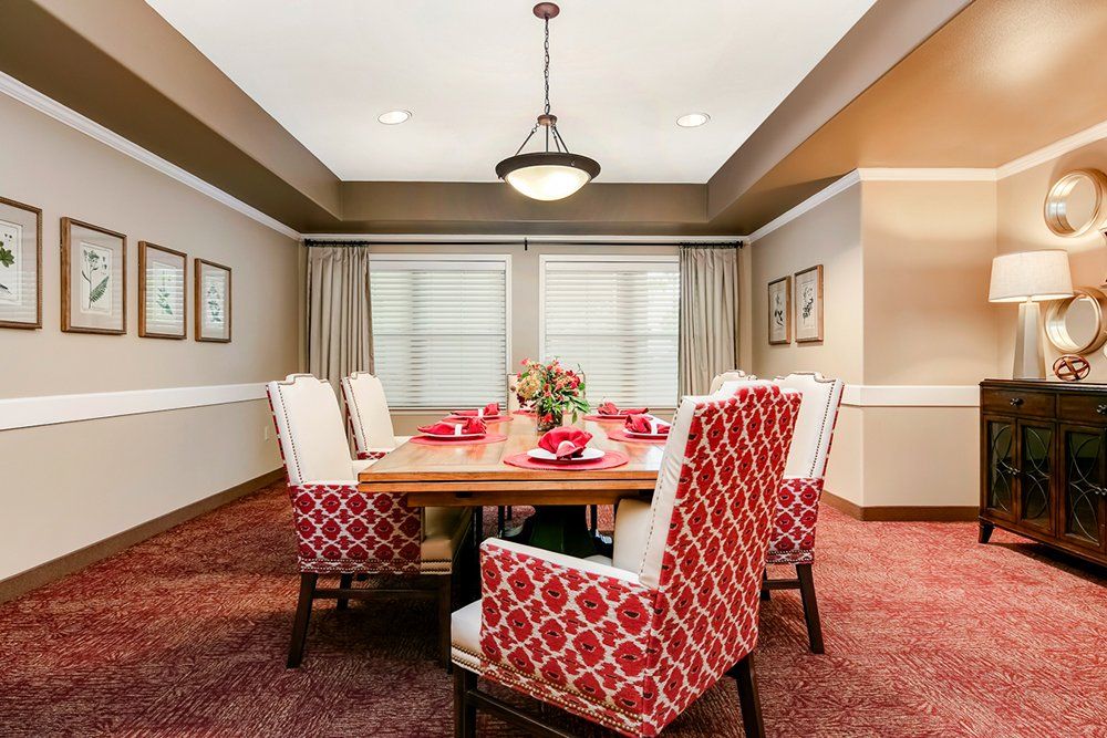 A cozy dining room with red patterned chairs and elegant lighting.