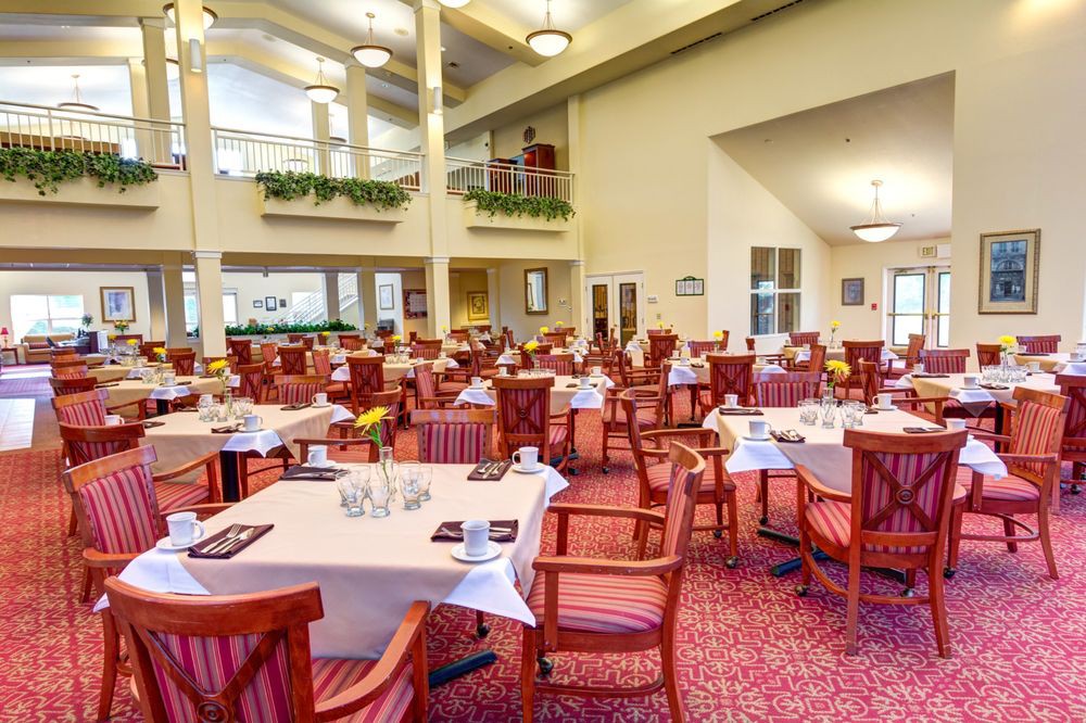 A spacious dining area featuring set tables with wooden chairs in an elegantly decorated restaurant.