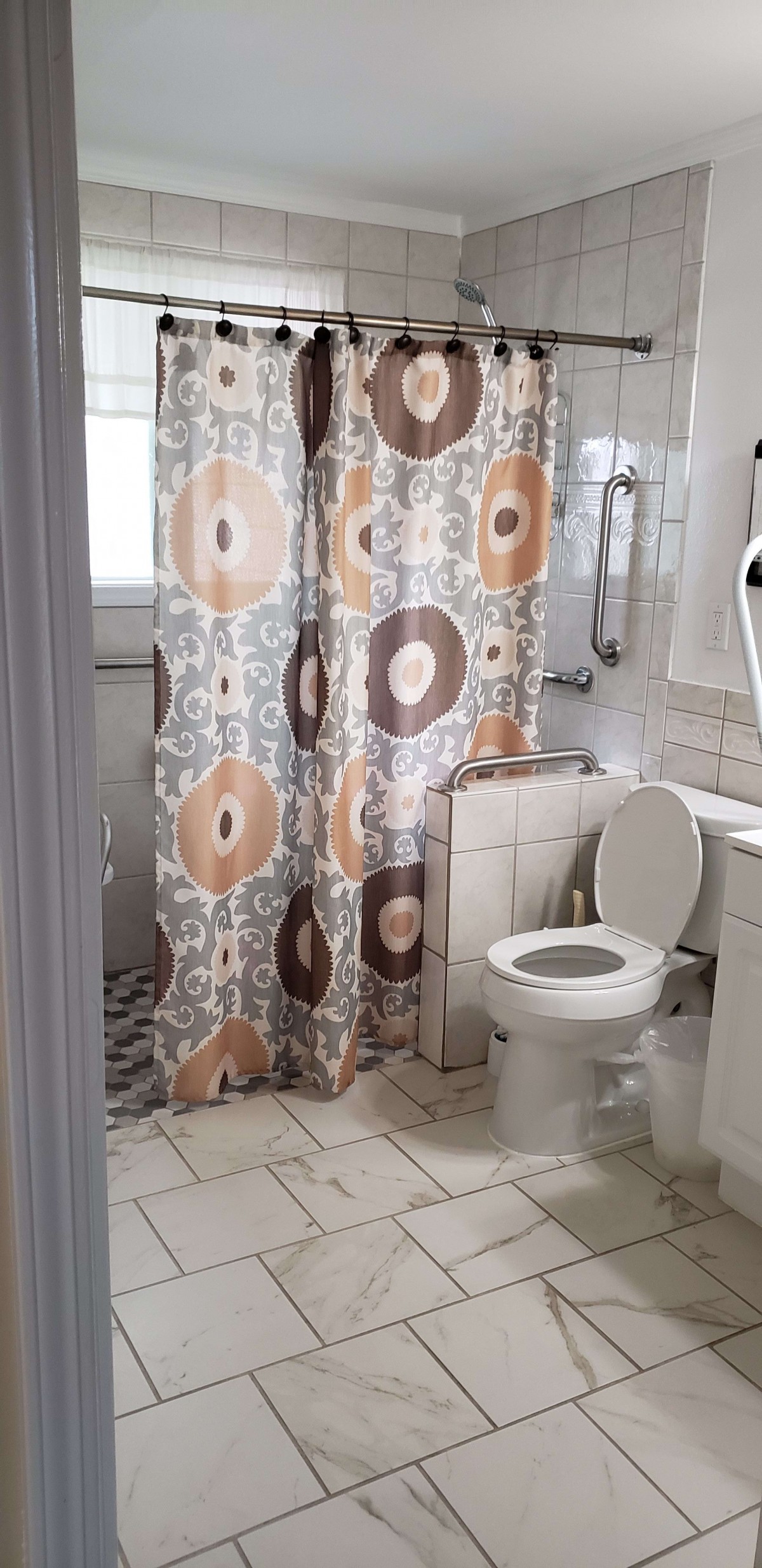 A bathroom with a patterned shower curtain and a toilet.
