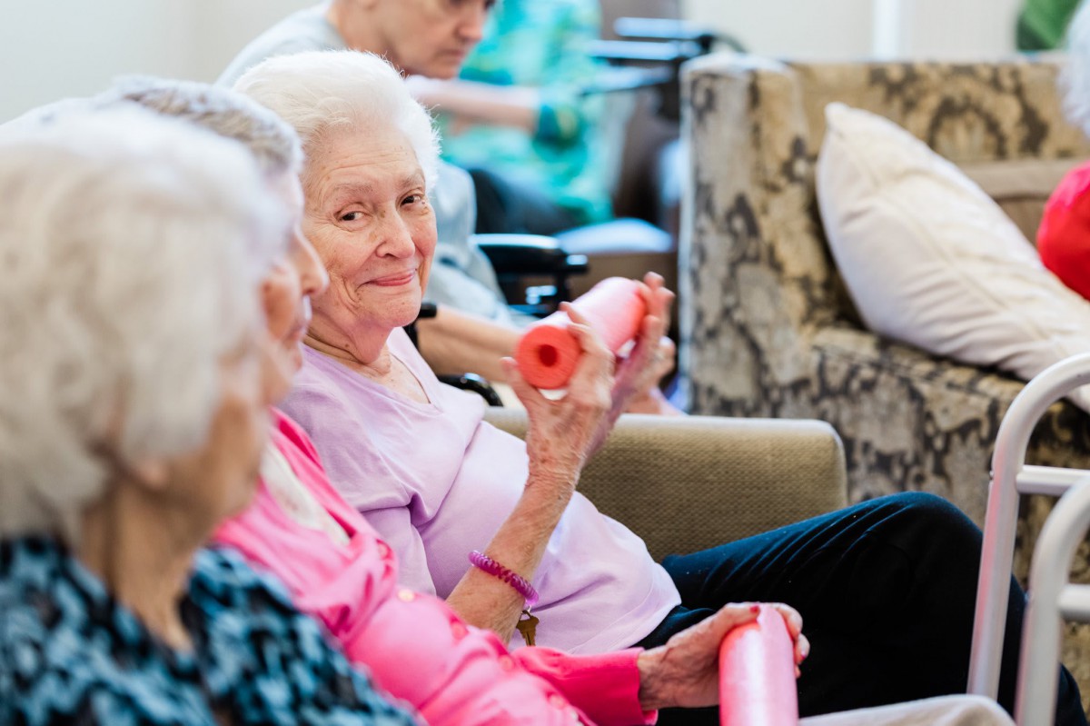 Elderly women participating in a group exercise session with small weights.