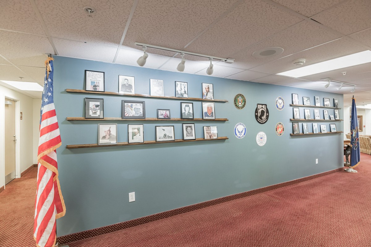 An art gallery wall showcasing a variety of framed artworks and photographs, arranged on shelves in a neat, organized manner.