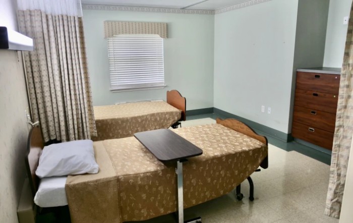 A clean hospital room with two beds and privacy curtains.
