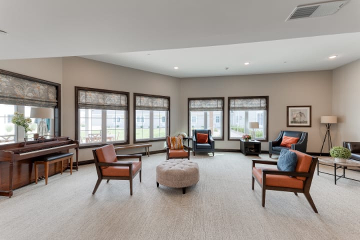 A spacious and modern living room with multiple windows, comfortable seating, and natural lighting.