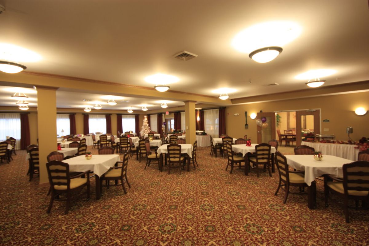 A spacious dining hall with neatly arranged tables and chairs on a carpeted floor.