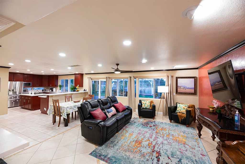 A cozy living room with an open floor plan connecting to the kitchen and dining area, featuring comfortable seating and warm decor.