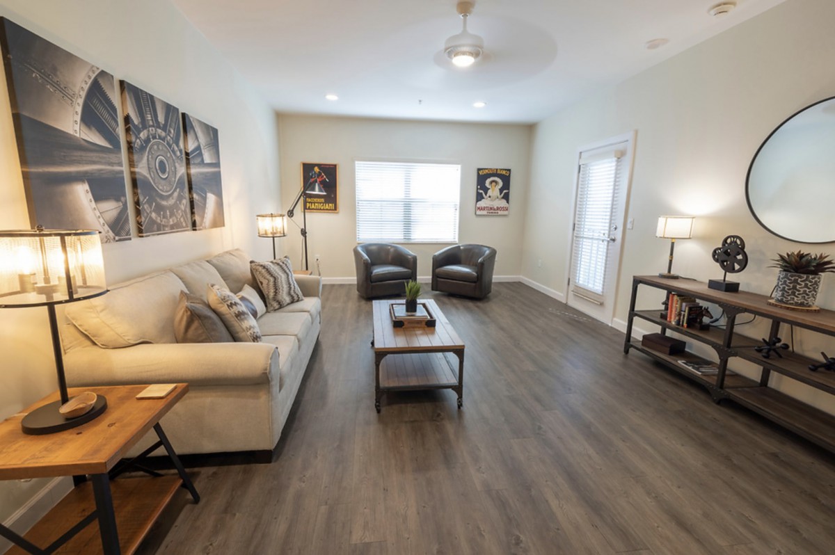 A cozy living room with modern furniture, featuring a sofa, two chairs, and a coffee table on wood flooring.