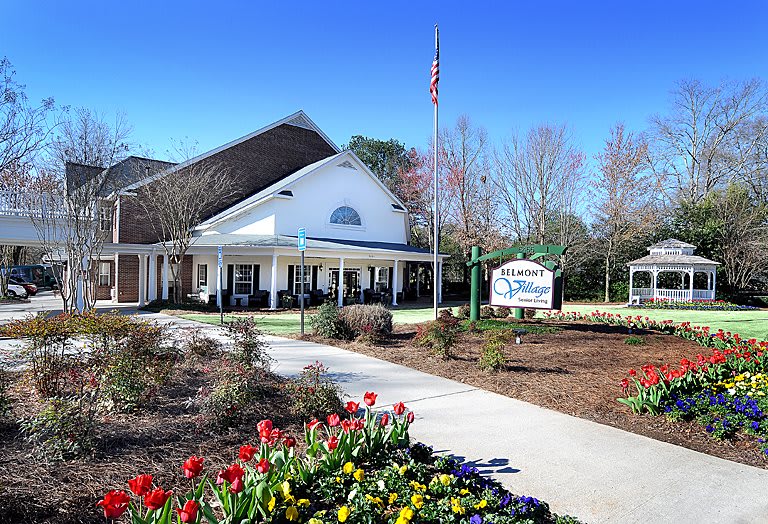 A welcoming building entrance flanked by a garden with colorful flowers.