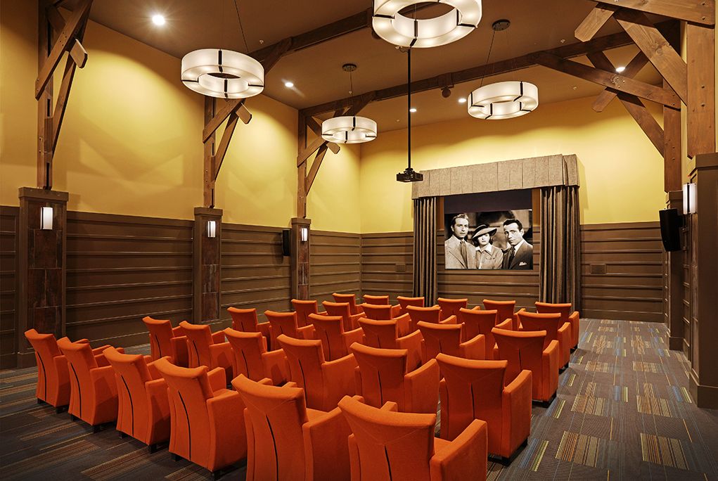 A cozy cinema with orange seats and a classic movie on the screen.