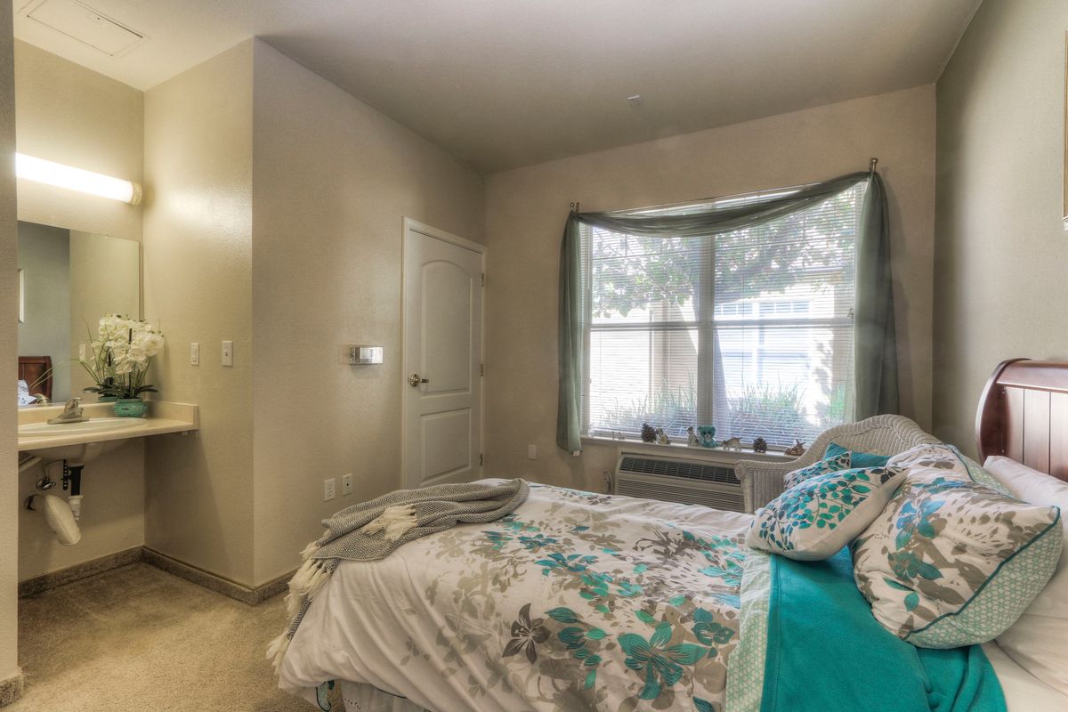 A cozy bedroom with a bed, window, and natural light filtering in.