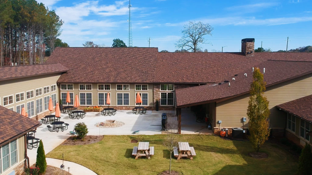 Outdoor patio area with tables and chairs adjacent to a large building on a sunny day.